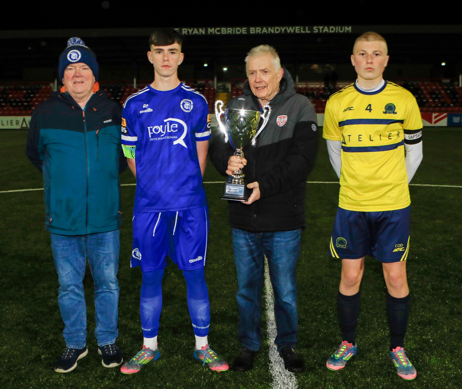 Don Gillespie presenting Andrew Gillespie (Rambo) Cup to Charlie McCleery, Trojans. Included, Don Boscos captain Caleb O'Doherty with on left Raymond Carton, Trojans FC.