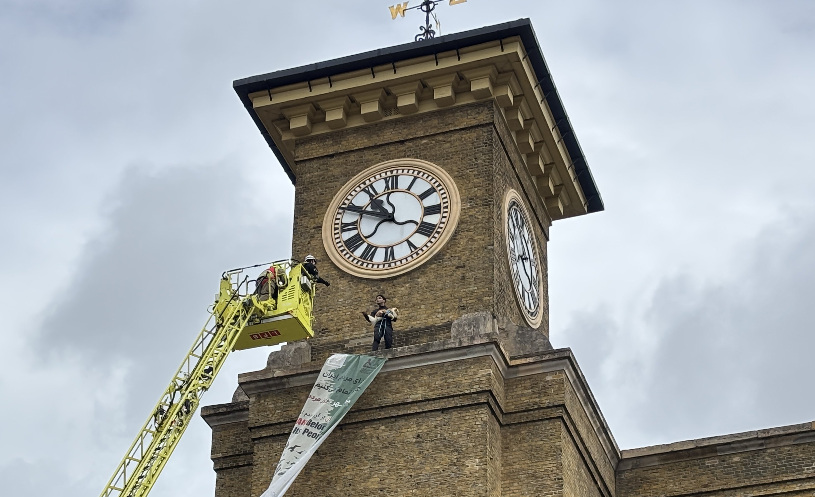 Protester clutching a dog climbs clocktower at mainline train station