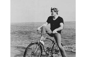 Richard Harris pictured sitting on a bicycle with a crown on his head on a beach at the waterside                      PICTURE: Richard Harris Archive, Ucc