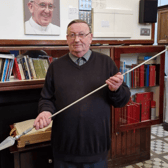 The late Fr Leo McDonnell holds the spear of the monument  to Archangel Michael which he commissioned the repair of
