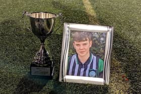 A framed picture of Kian alongside the NIYFA U18 National League trophy.