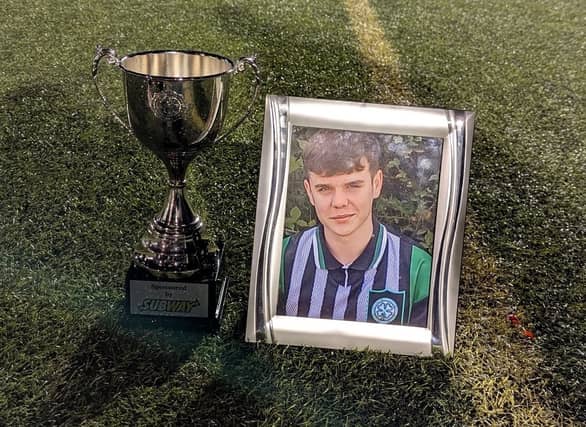 A framed picture of Kian alongside the NIYFA U18 National League trophy.