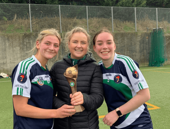 Eve Schneider, múinteoir Caoimhe Esselmont, and Ríona Ní Chrualaoich with the league winners’ trophy