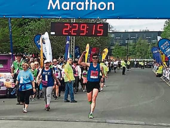 A delighted Colin Griffin raises his arm as he crosses the line in fifth place in Monday's Belfast City Marathon. Photo by Ryan Maxwell