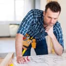 Building contractor bending over home plans