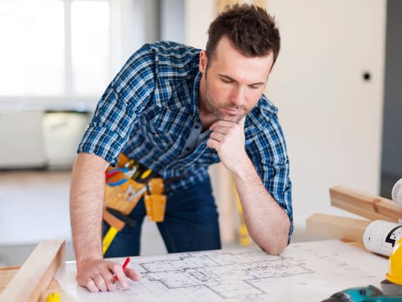 Building contractor bending over home plans