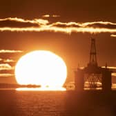 An oil platform at sea, next to the sun rising