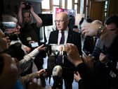 John Swinney speaking while surrounded by members of the press