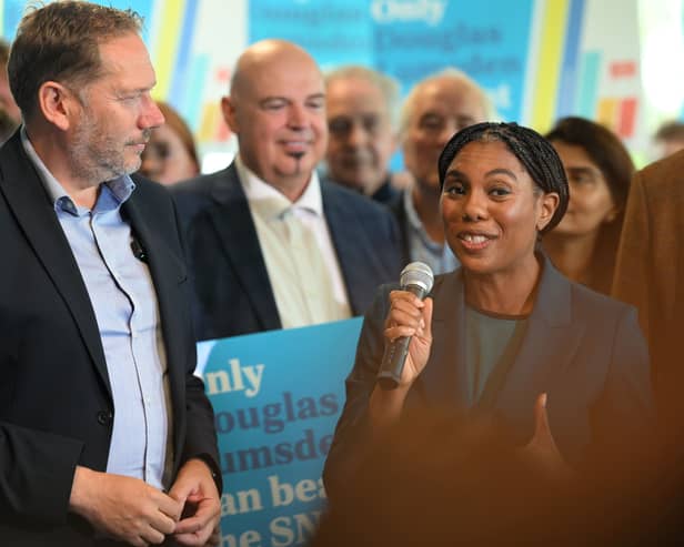 Kemi Badenoch speaking into a mic, alongside Douglas Lumsden and Tory campaigners