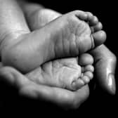 A black and white photo of a baby's feet in an adult's hand