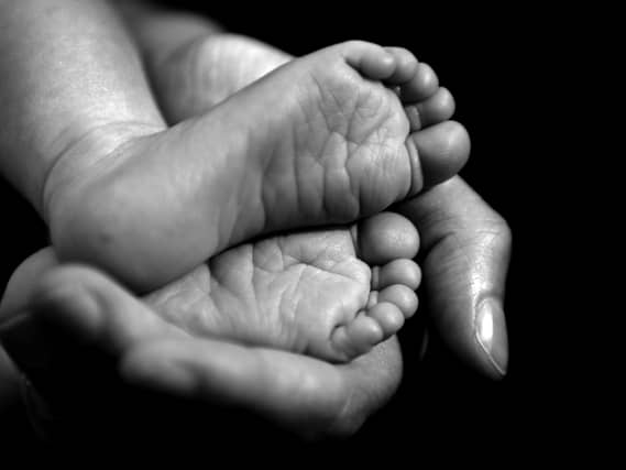 A black and white photo of a baby's feet in an adult's hand