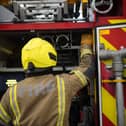 A firefighter at the back of a fire engine
