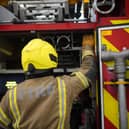 A firefighter at the back of a fire engine