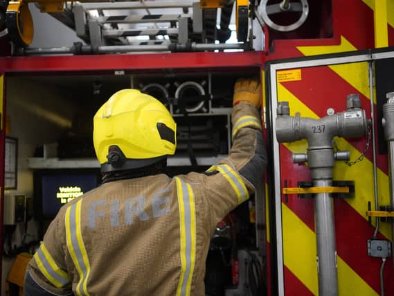 A firefighter at the back of a fire engine