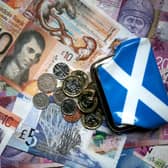 Bank notes and coins sit with a saltire design purse