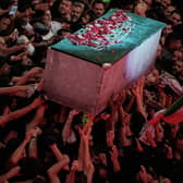 The flower petal-covered coffin of the late Iranian Supreme Leader Ayatollah Ali Khamenei is carried above mourners