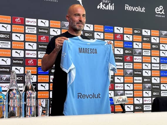 Manchester City manager Enzo Maresca holds up a club shirt with his name on during his introductory press conference