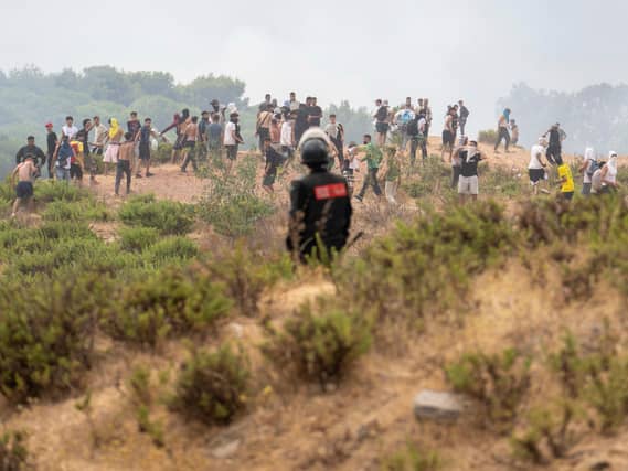 A member of the Moroccan security forces stands guard as people attempt to cross to the Spanish enclave of Ceuta