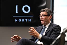 Andy Burnham talks in front of a TV screen with a logo for Number 10 North