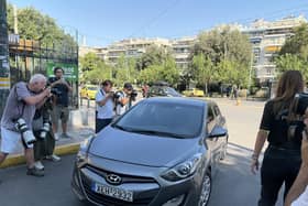 Photographers surrounding a grey car