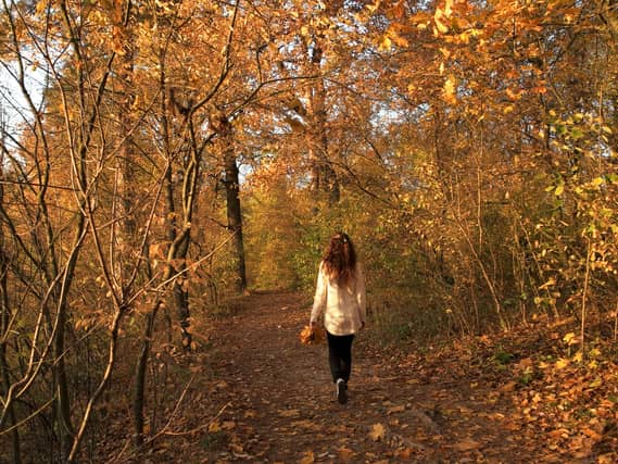Casual woman walking in colourful park (Alamy/PA)