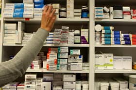 A pharmacist reaching for medicines on a shelf