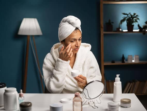 Happy woman with towel on head doing skincare routine