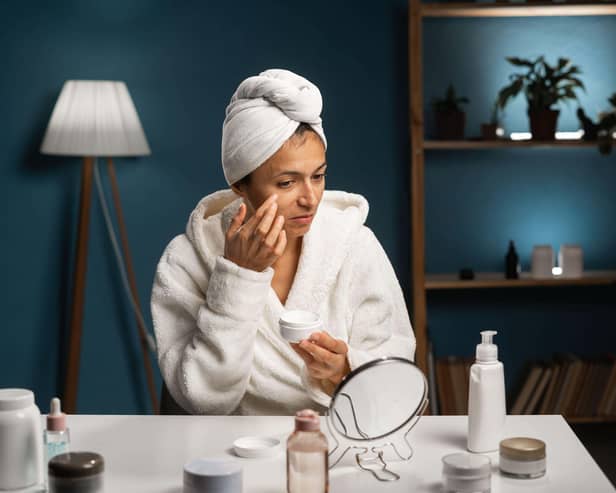 Happy woman with towel on head doing skincare routine