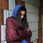 A distressed looking young person in an alleyway