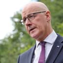 Headshot of John Swinney speaking outside, with trees behind him