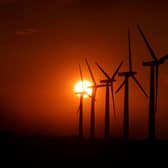 View of wind turbines, with the sun setting behind him
