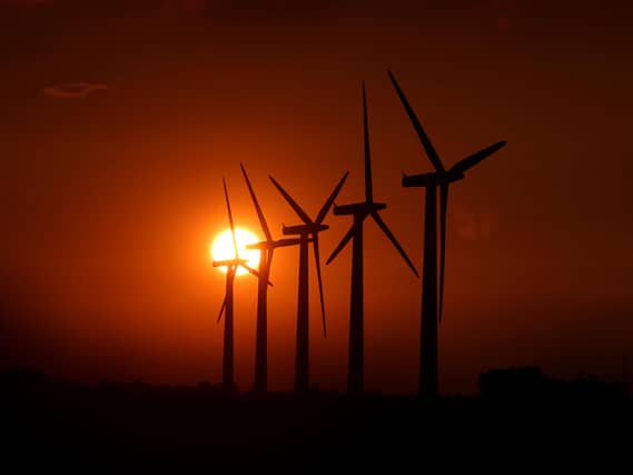 View of wind turbines, with the sun setting behind him