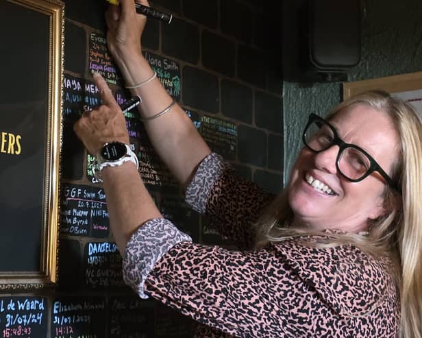 Grace McLaughlin smiling while signing her name on a board