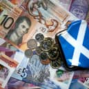 A saltire design purse sits on top of bank notes and coins