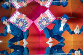 A person holding up a Fringe programme, who is then reflected in several mirrors