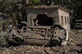 A local resident stands next to destroyed cars after an overnight Russian attack on Kyiv, Ukraine