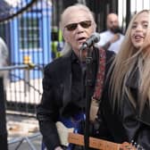 Brian Hyland and Ashleigh Harley playing guitars and singing outside Downing Street.