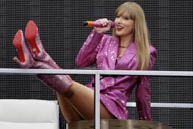 Taylor Swift smiling while performing, wearing a pink sparkly blazer and boots