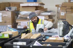 A work packs goods into trays in a warehouse