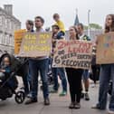 Protesters holding up placards with comments including 'real men care for their children' and 'invest in families, invest in the future'