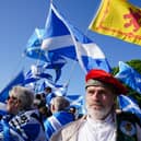 Independence supporters waving Scottish flags, standing outside under blue skies