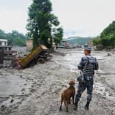 A policeman with a sniffer dog in the aftermath of flash floods