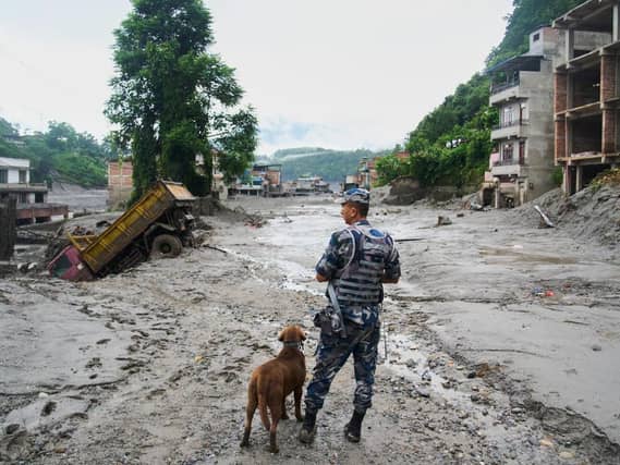 A policeman with a sniffer dog in the aftermath of flash floods