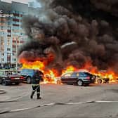 Firefighters tackle cars on fire, with thick black smoke rising above them
