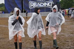 Festivalgoers cover up with plastic ponchos for the heavy rainfall at the Reading Festival at Little John’s Farm, Reading, Berkshire.