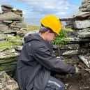 A person in a hard hat working within a ruin