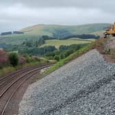 Digger at the top of embankment beside railway