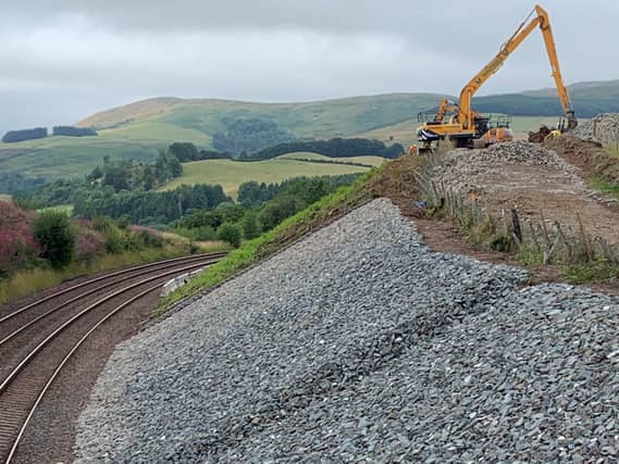 Digger at the top of embankment beside railway