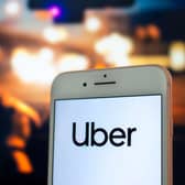 An iPhone with the Uber app open being held by a passenger in the back seat of a car