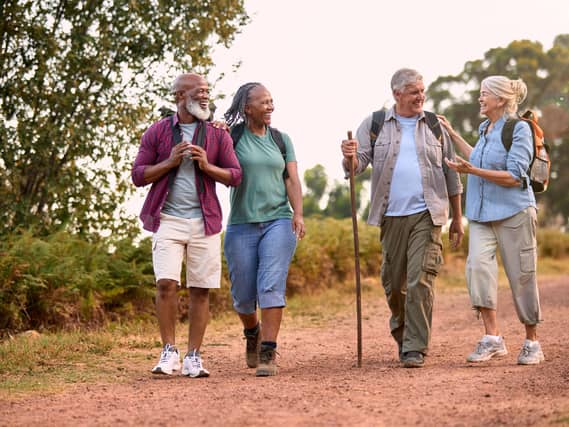 Group of active senior friends enjoying hiking through countryside